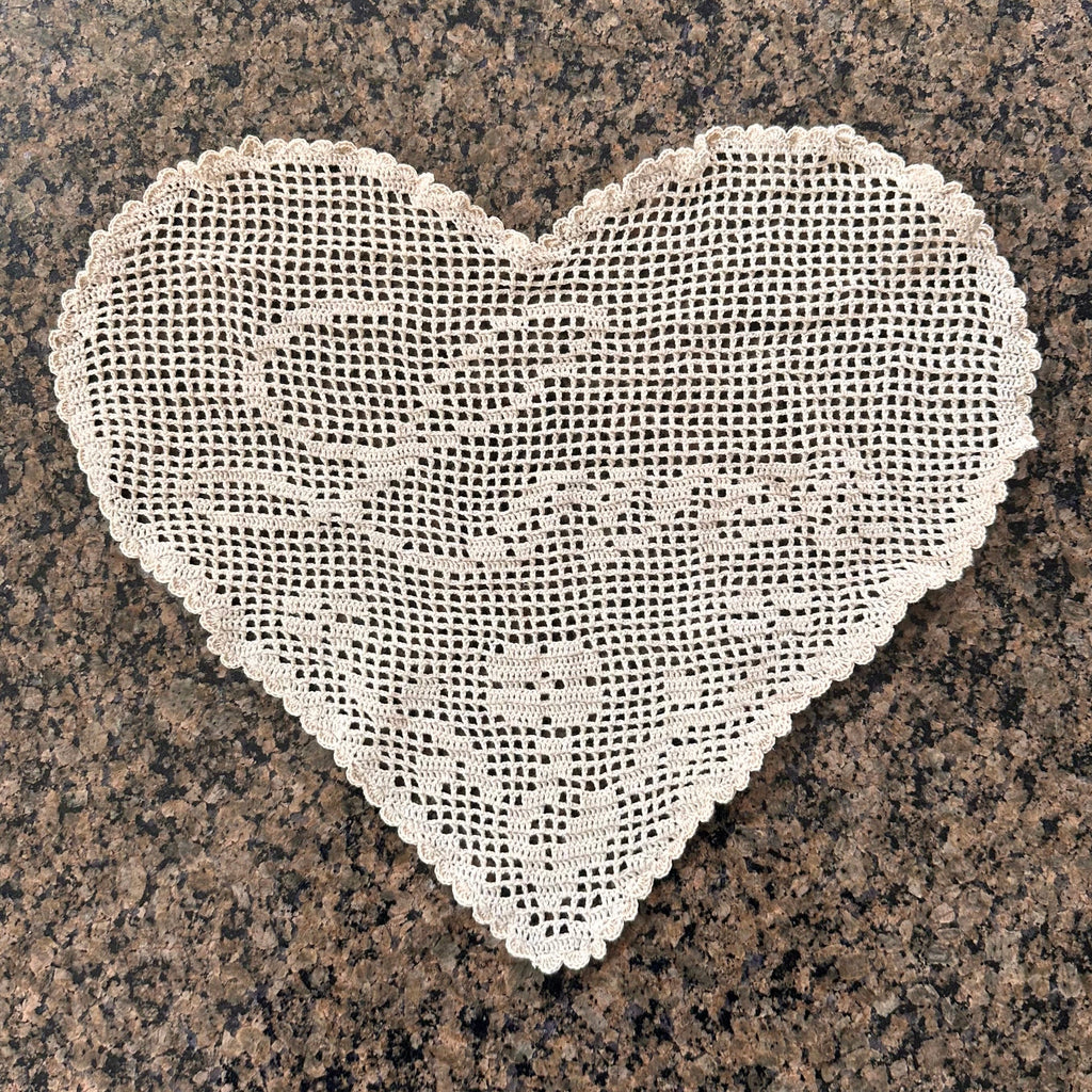 one heart-shaped crochet lace doily on a granite surface