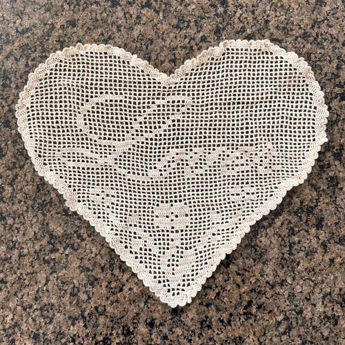one heart-shaped crochet lace doily on a granite surface