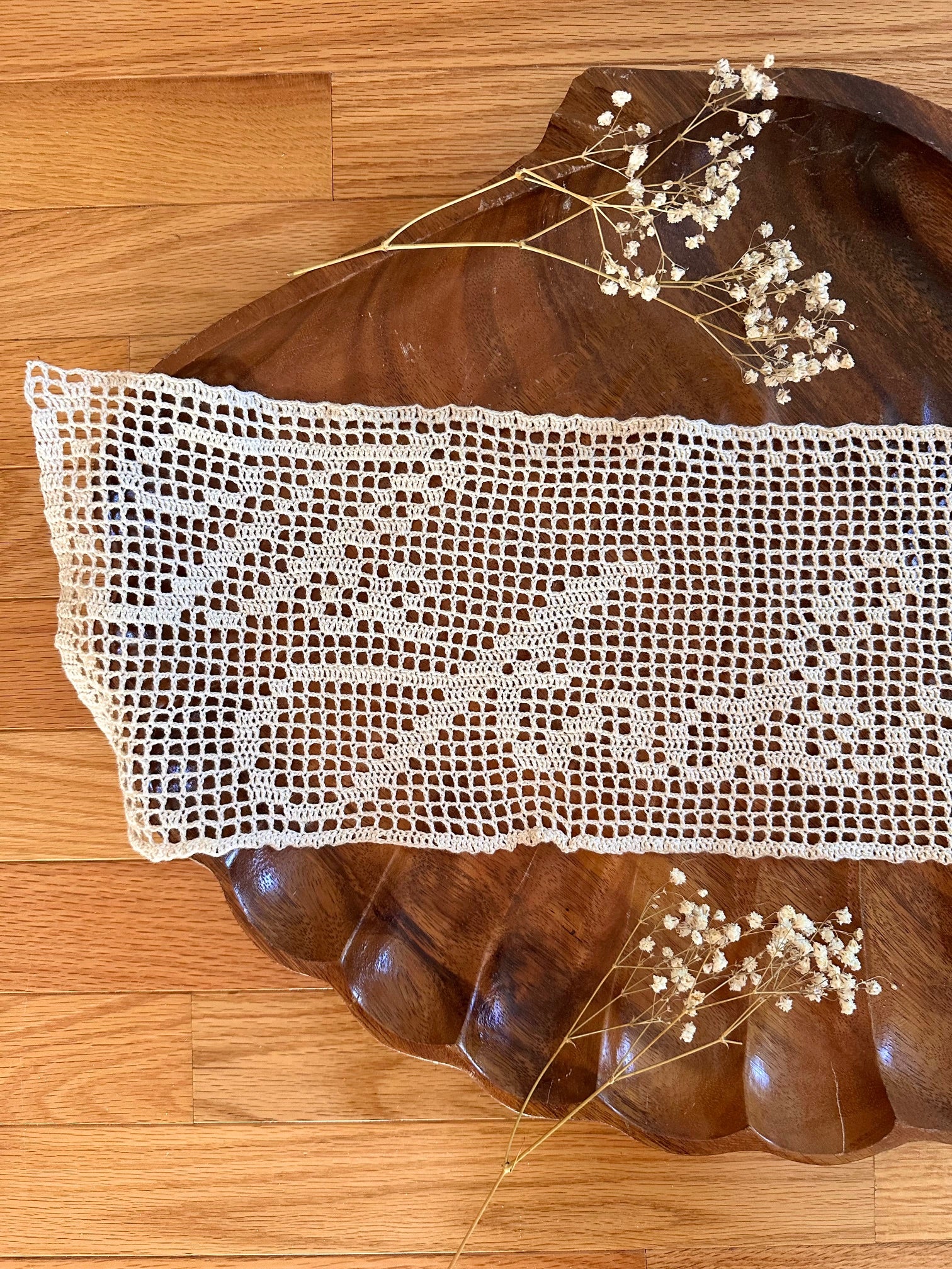 Decorative wooden tray with lace doily and dried flowers on a wooden floor