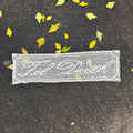 White lace filet crochet textile on dark pavement with scattered yellow leaves